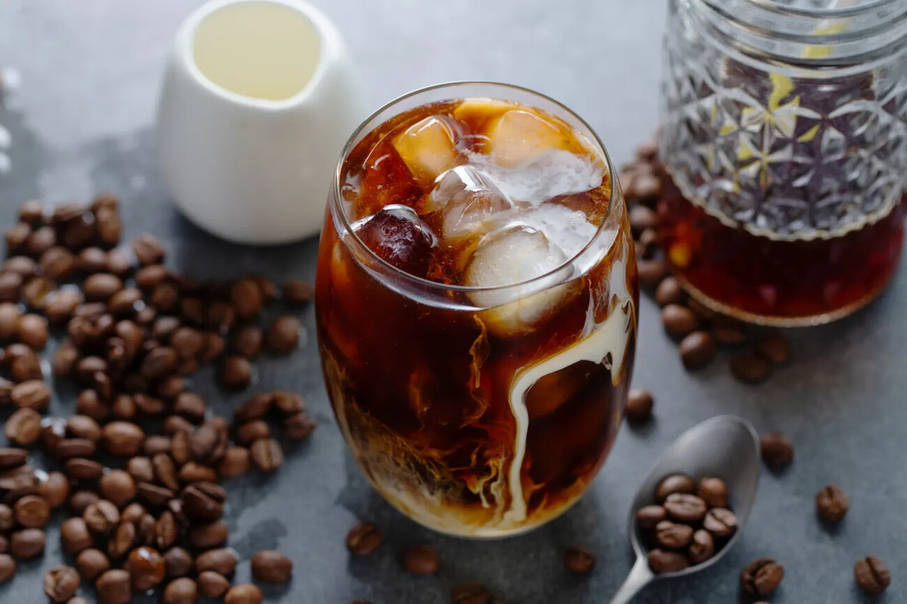 Tasty refreshing iced coffee with ice cubes in glasses on bright background. Closeup; Shutterstock ID 2025940094